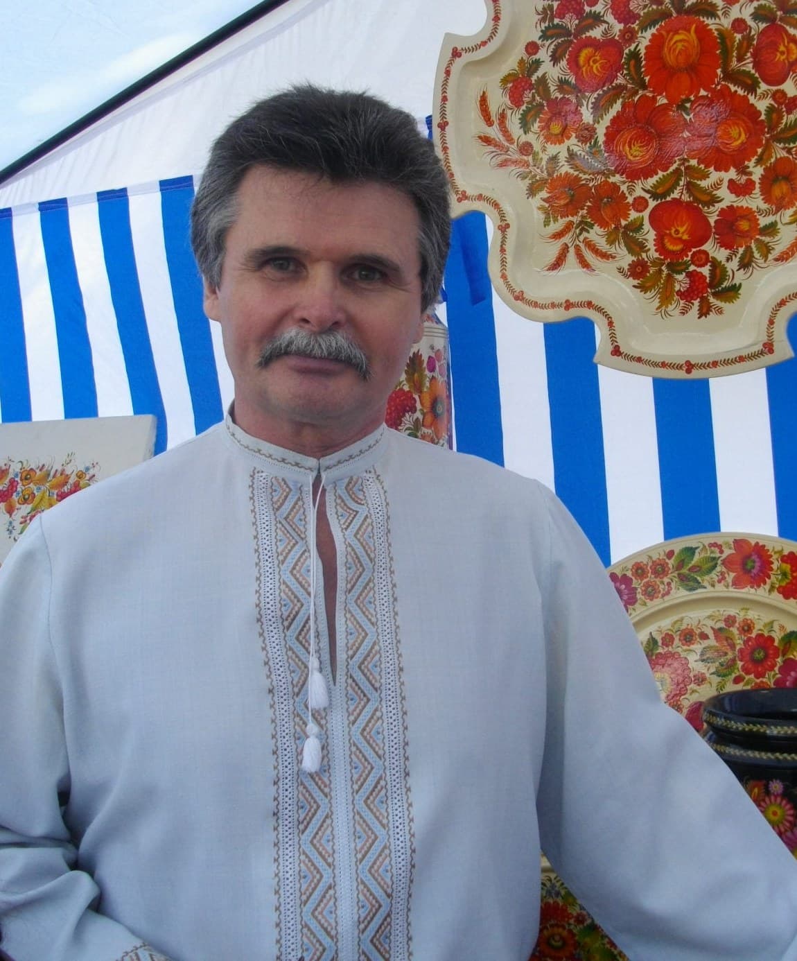 Andrii Pikush among his painted wooden trays