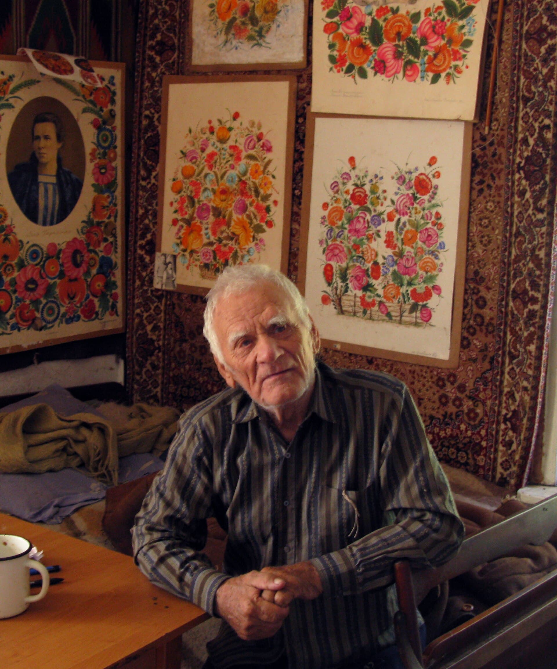 Vasyl Sokolenko at home in 2016, his own paintings on the wall behind him
